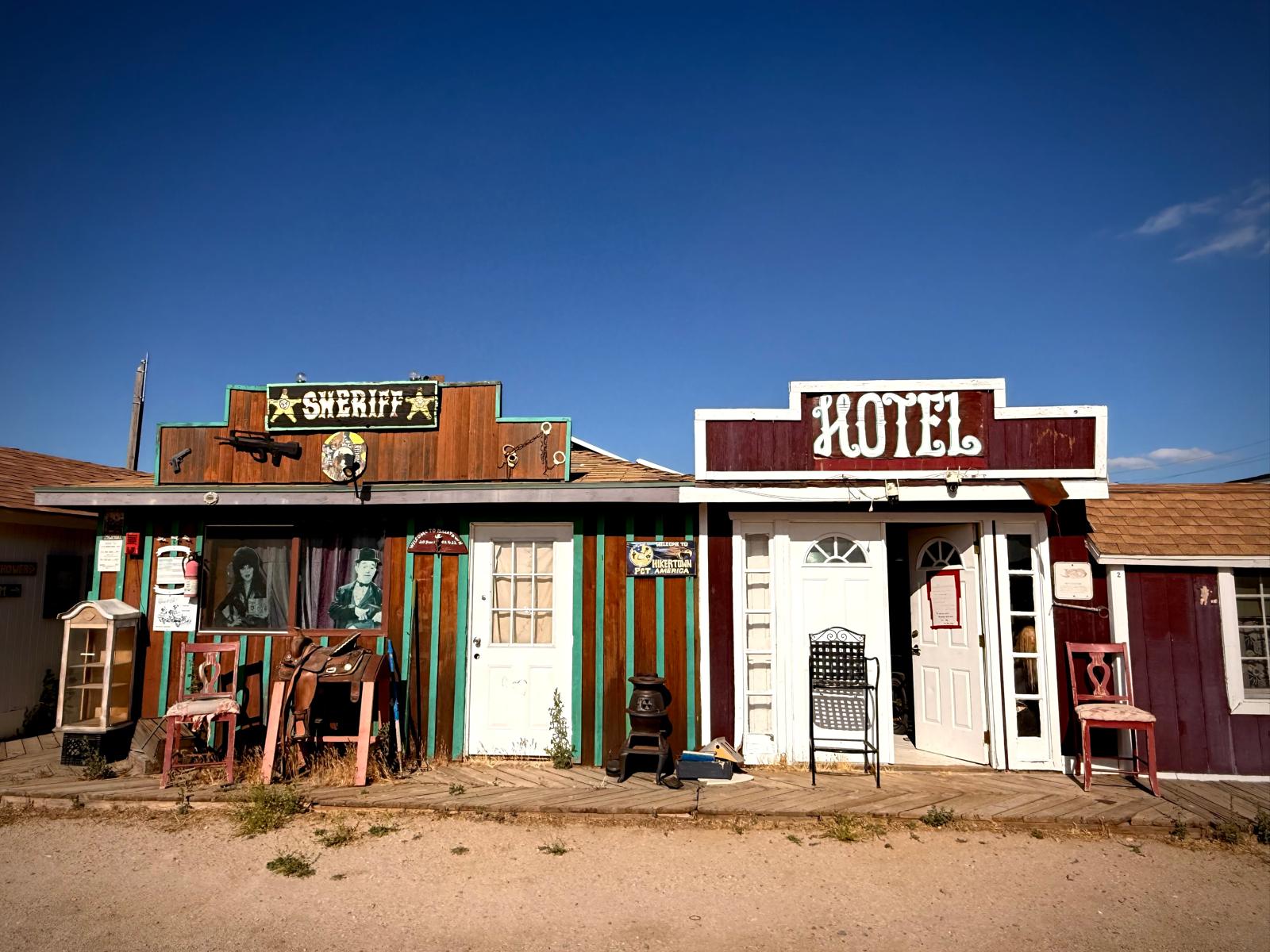 The Hikertown hotel and sheriff storefronts under a hard desert sky