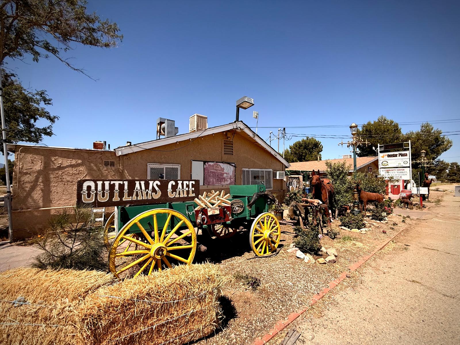 The Outlaws Cafe sign and an old wagon outside the roadside cafe